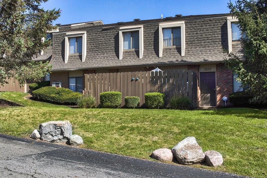 A house with a brown roof and a grey wall with a white door.