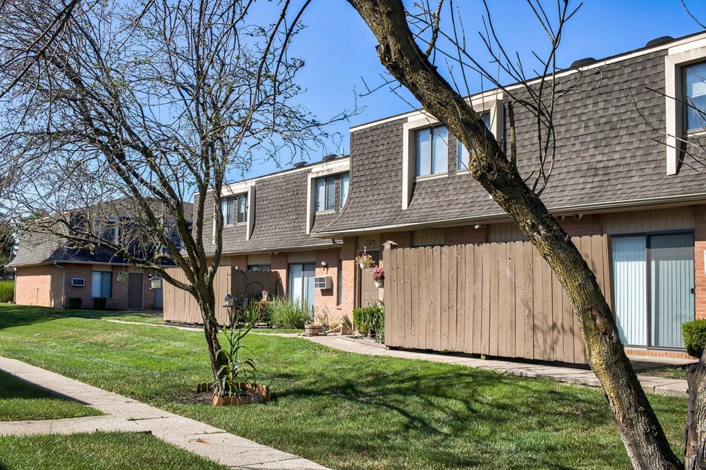 A tree in front of a building with a brown roof.