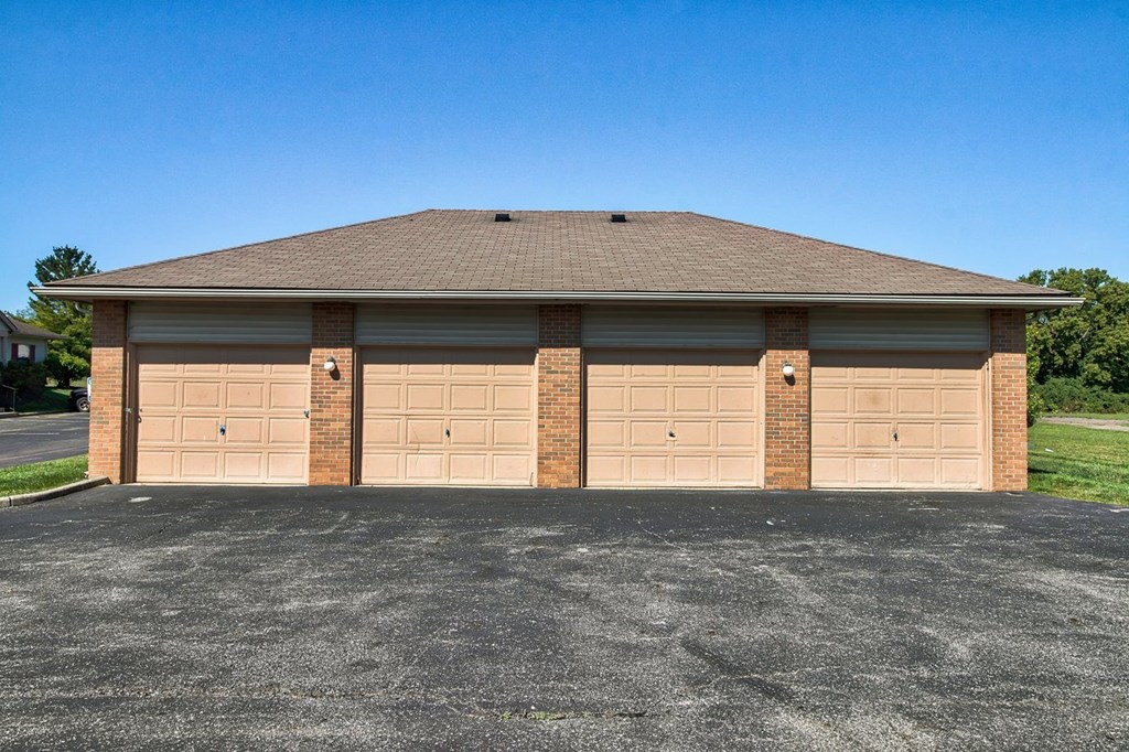 A two-car garage with a brick pillar and tan doors.