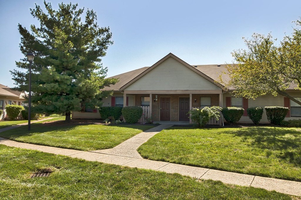 A house with a well-maintained lawn and a sidewalk in front.
