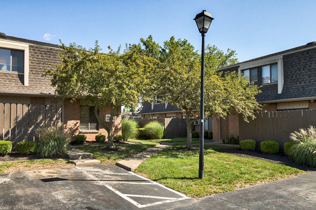 A black lamp post stands in a driveway with a house in the background.