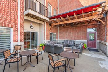 A patio with a table and chairs is surrounded by a brick building.