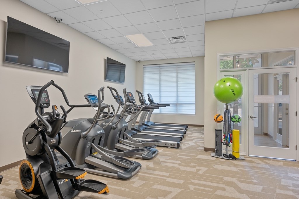 A gym with treadmills, exercise bikes, and a television.