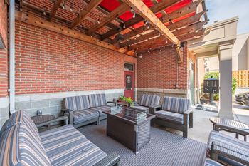A patio with a red brick wall and striped couches.
