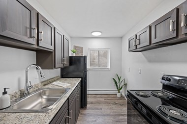 a kitchen with dark cabinets and a stainless steel sink