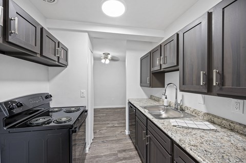 a kitchen with dark cabinets and granite countertops