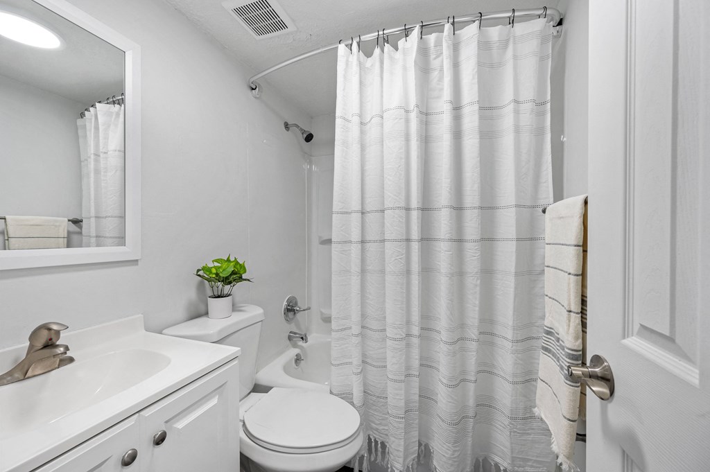 a bathroom with a white sink and toilet and a white shower curtain