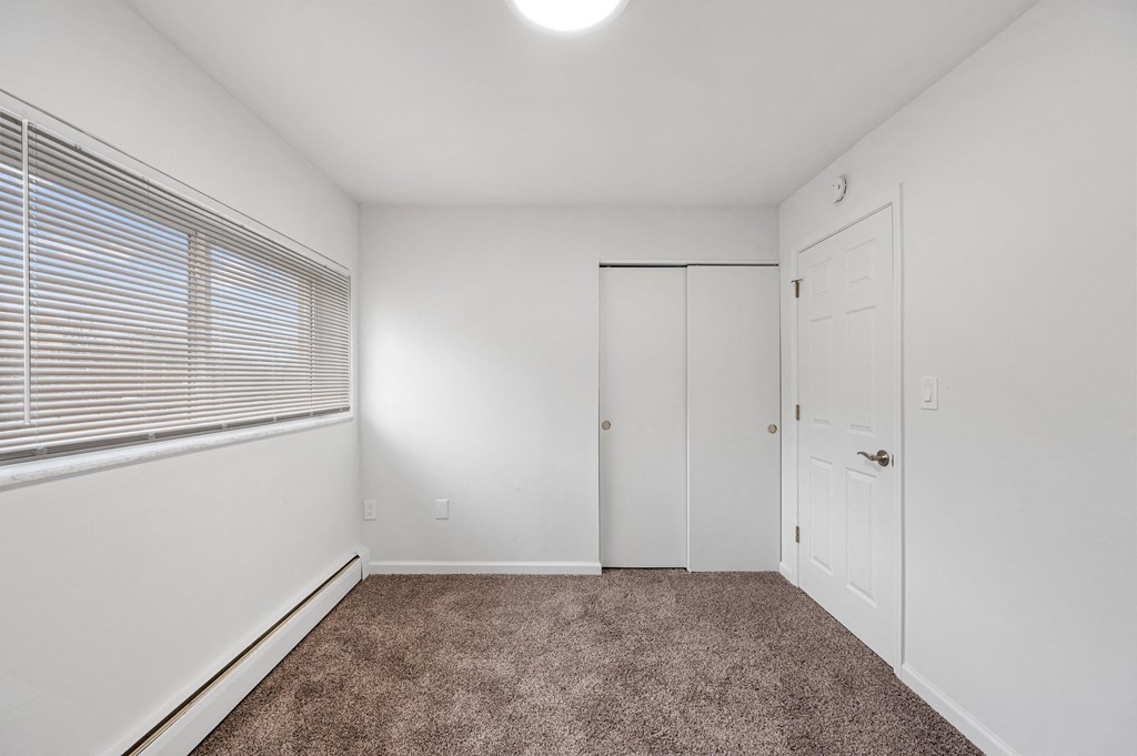 a bedroom with white walls and carpet