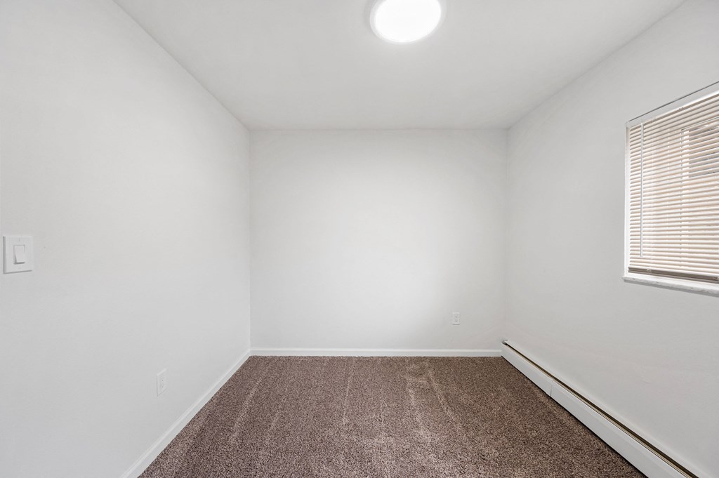 a bedroom with white walls and a carpeted floor