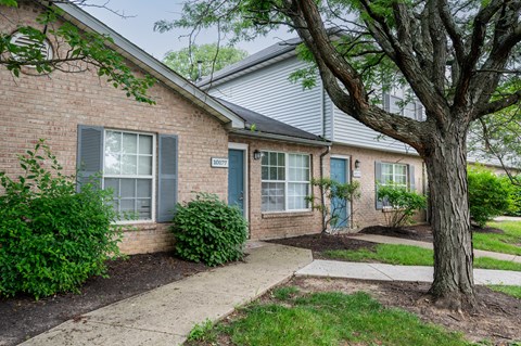 A house with a blue door and a tree in front.