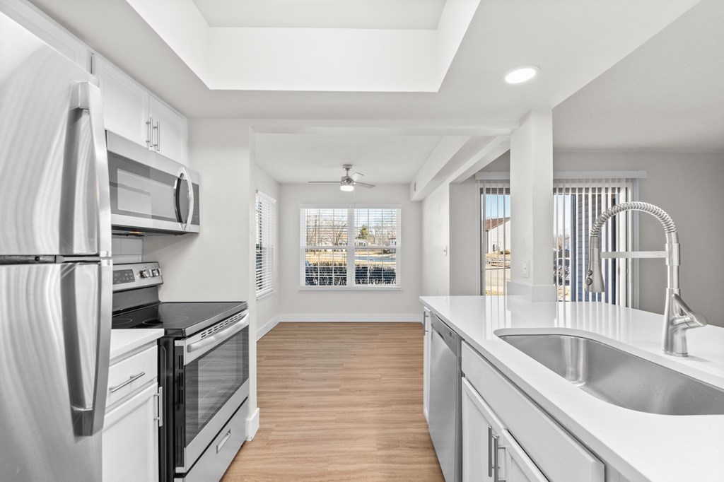 A modern kitchen with stainless steel appliances and wooden flooring.