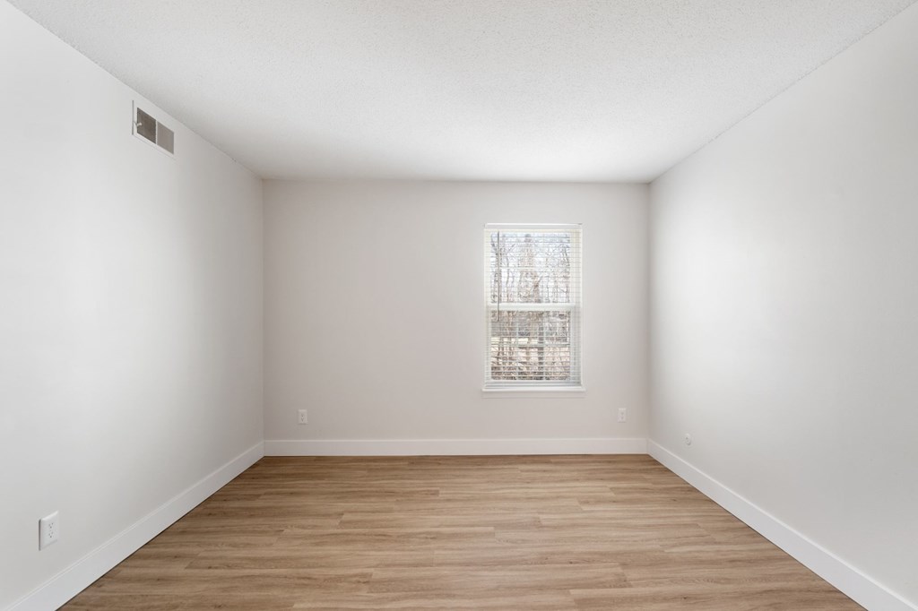 A room with a window and wooden flooring.