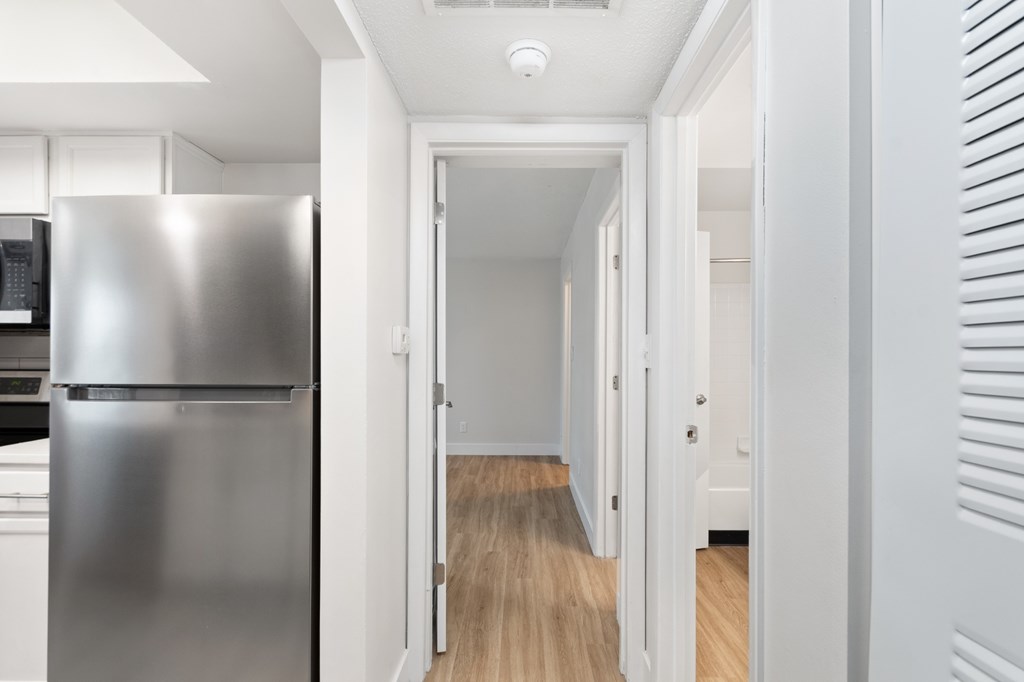 A long hallway with a refrigerator on the left.