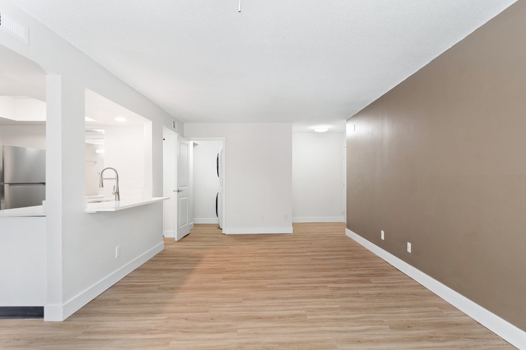 A long, empty hallway with white walls and wood flooring.