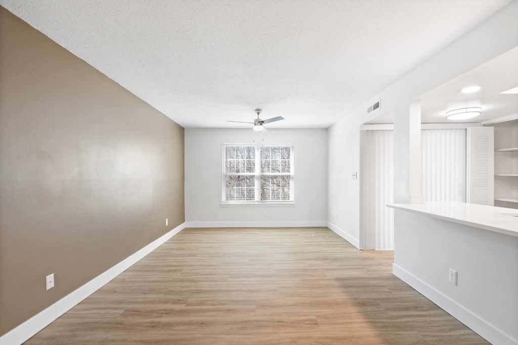 A spacious room with wooden floors and a ceiling fan.
