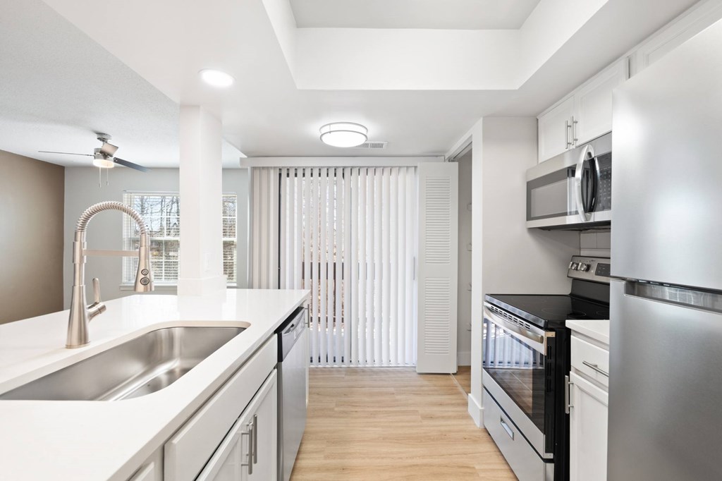 A modern kitchen with stainless steel appliances and white countertops.