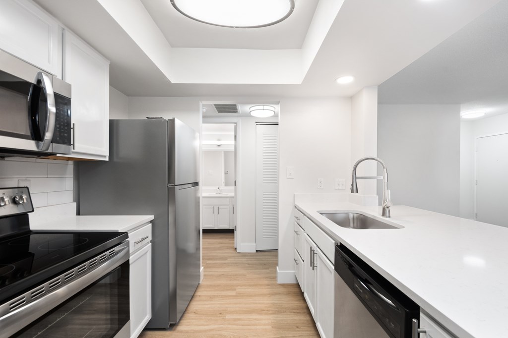 A modern kitchen with stainless steel appliances and white cabinetry.
