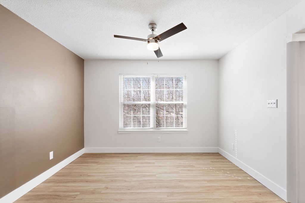 A room with a ceiling fan and a window with blinds.