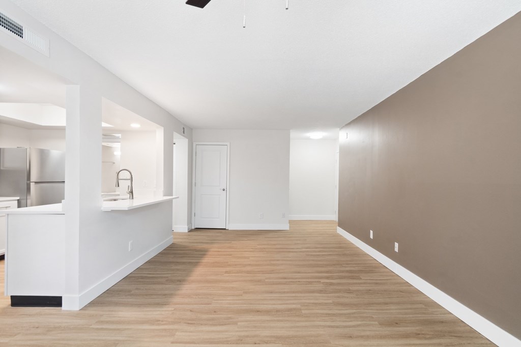 A room with a white kitchen area and a wooden floor.