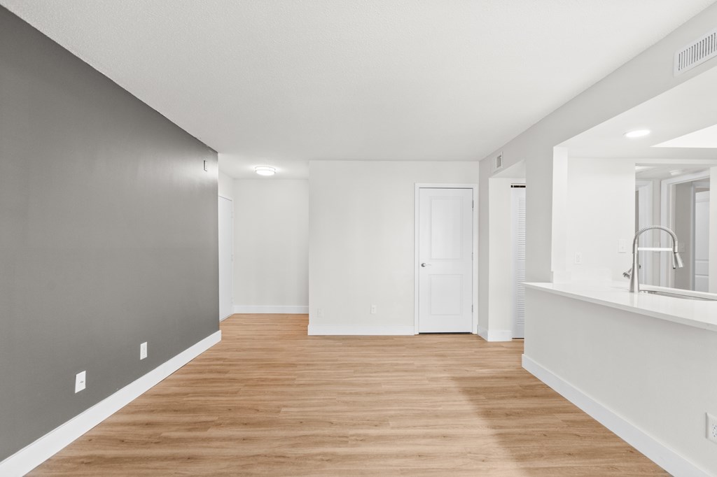 A long, empty room with wooden floors and white walls.