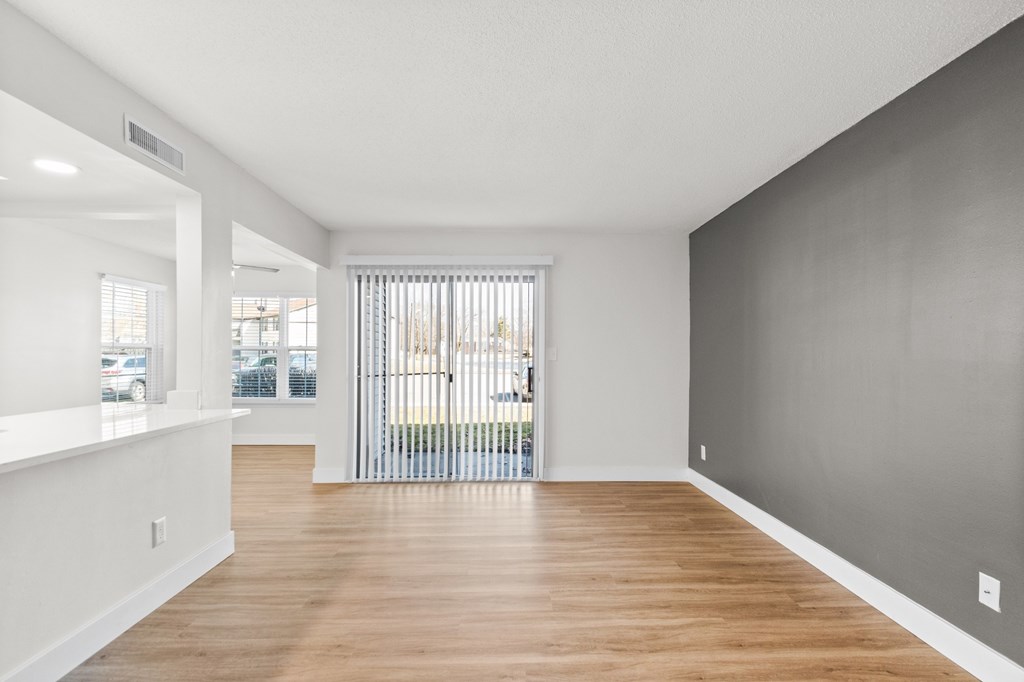 A spacious room with wooden floors and white walls.