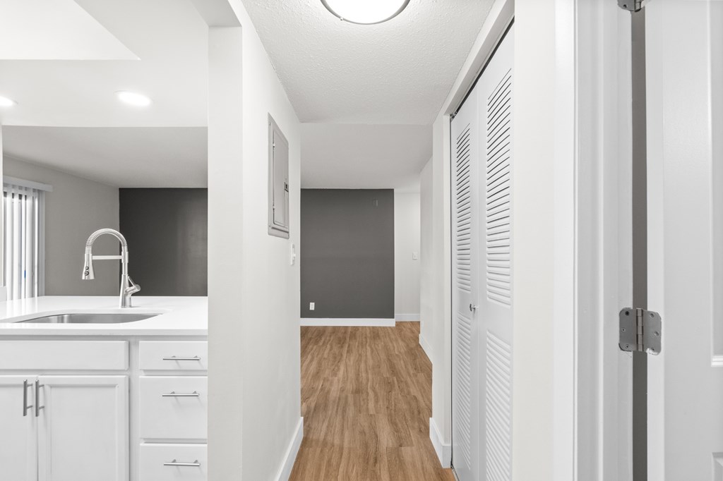 A modern kitchen with white cabinets and a wooden floor.