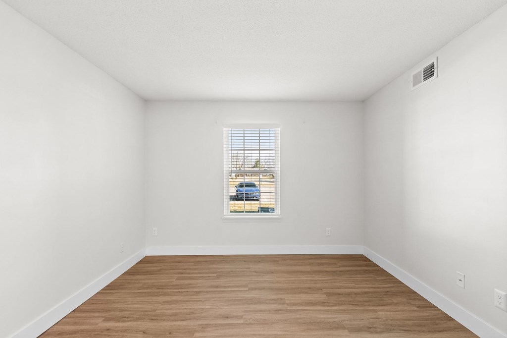 A room with a window and wooden flooring.