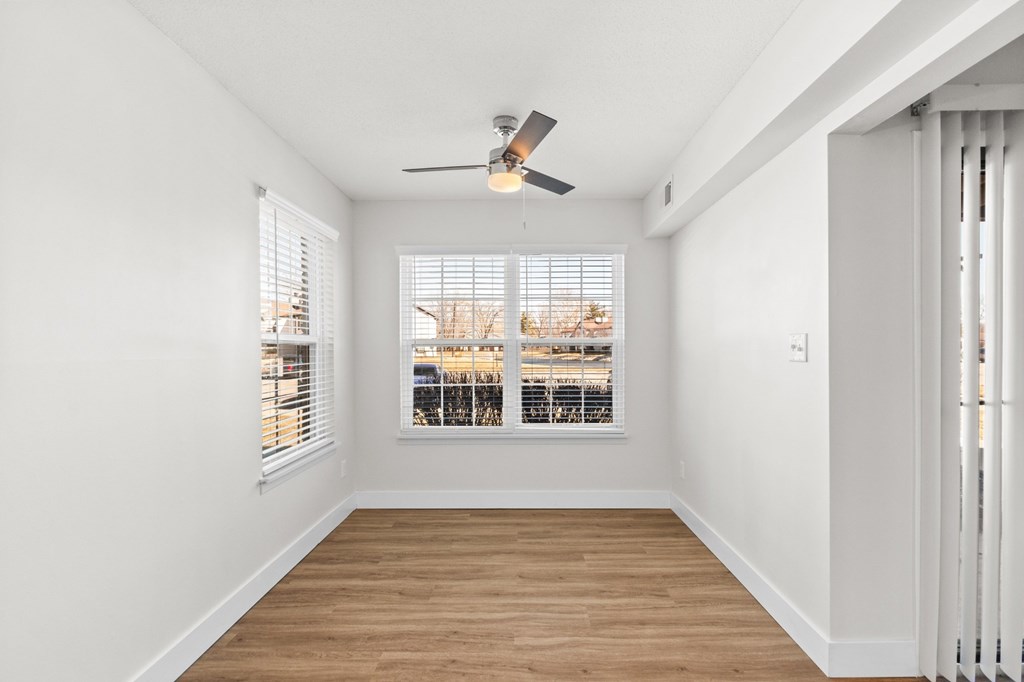 A room with a ceiling fan and a window overlooking a cityscape.