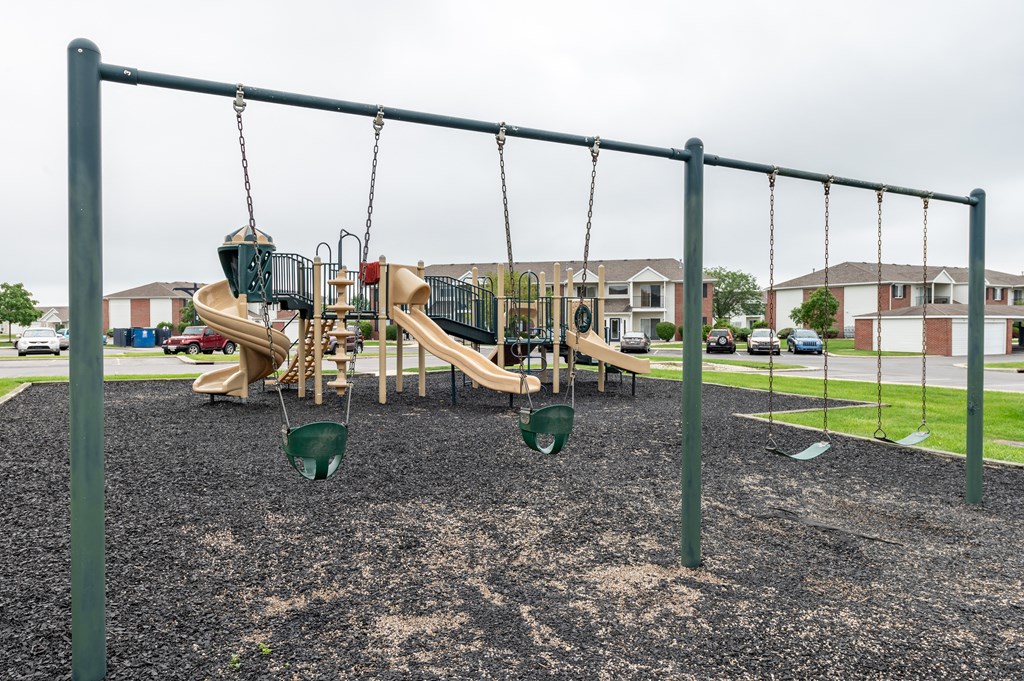 a playground with swings and slides in a park at Crystal Glen Apartments, Findlay, OH, 45840