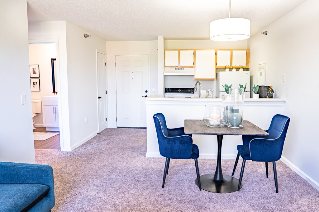 a dining area with a table and chairs and a kitchen in the background
