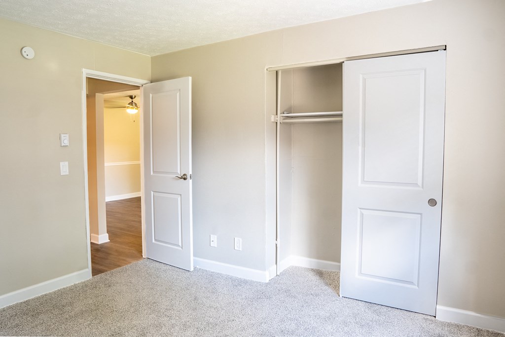 a bedroom with two doors and a hallway in the background