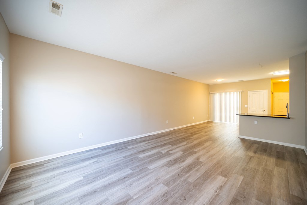 an empty living room with wood floors and white walls at Traditions at Slate Ridge, Reynoldsburg