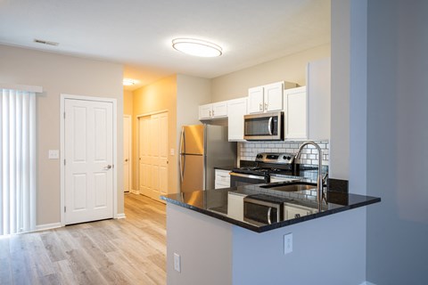 a kitchen with a black counter top and a stainless steel refrigerator