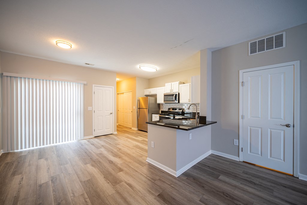 a living room with a kitchen and a door to a hallway at Traditions at Slate Ridge, Reynoldsburg, 43068