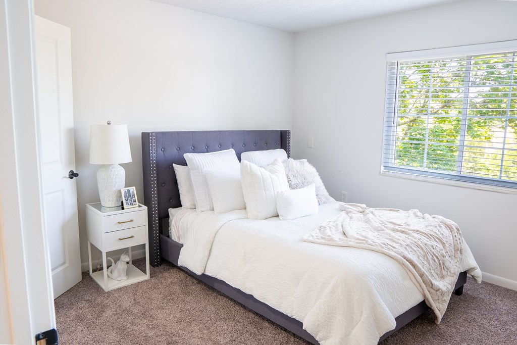 a bedroom with a bed and a nightstand with a lamp