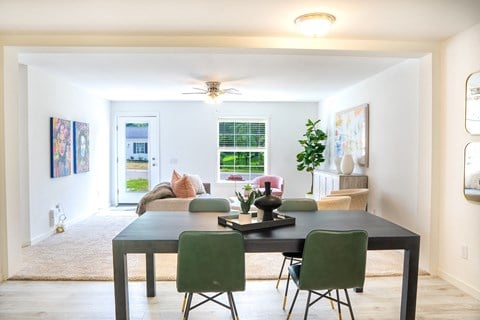 a living room with a large table and green chairs