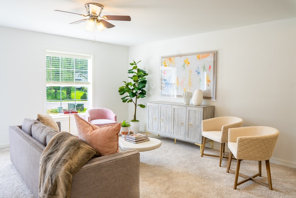a living room with white walls and a ceiling fan