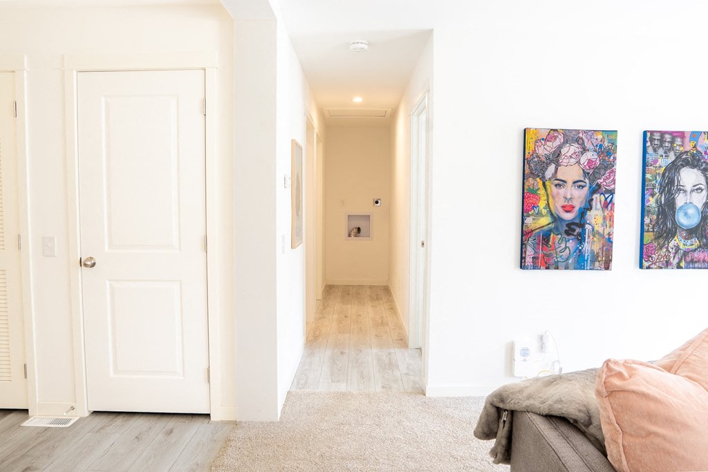 a hallway with two paintings on the wall and a couch in the foreground