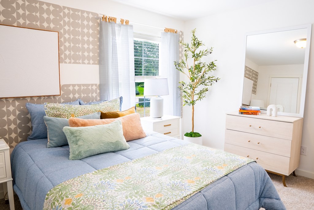 a bedroom with a bed and a dresser with a mirror