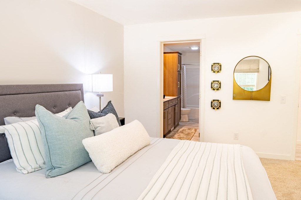 a bedroom with a large bed and a bathroom in the background