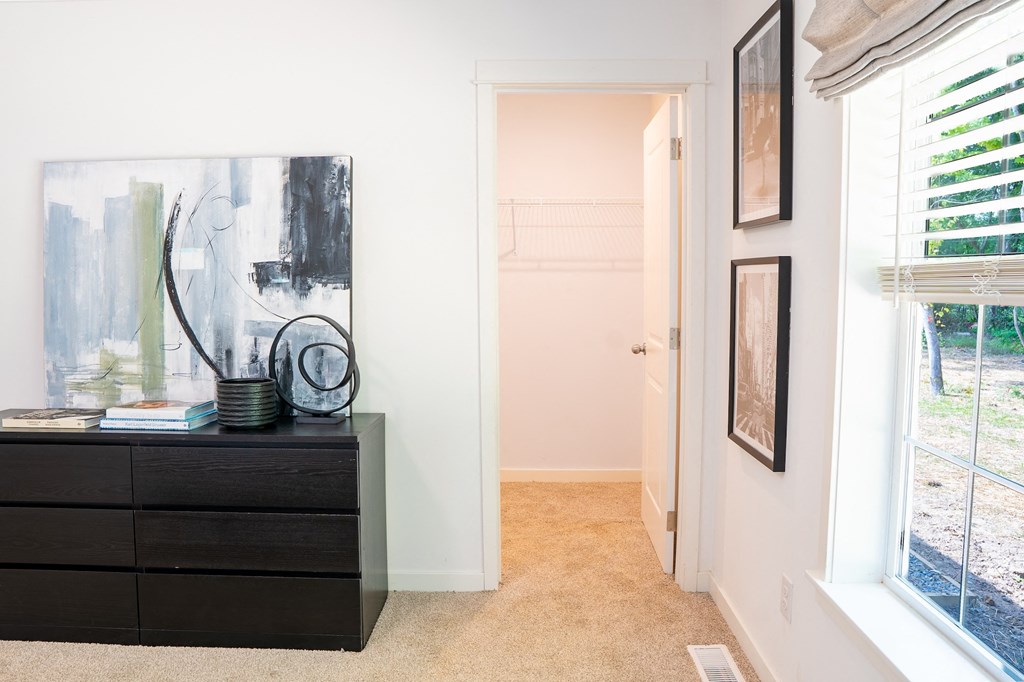 a bedroom with white walls and a black dresser with a large painting on top of it