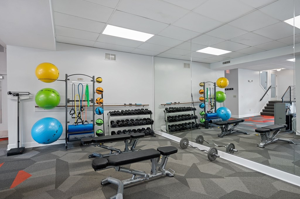 A gym with a variety of equipment including weights and exercise balls.