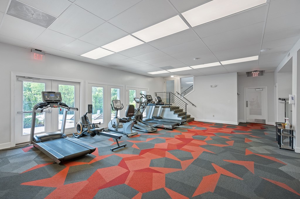 A gym with treadmills, exercise bikes and a staircase.