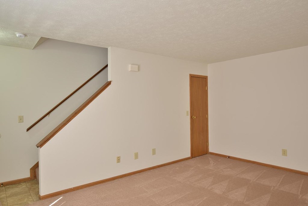 A room with a wooden door and a staircase.