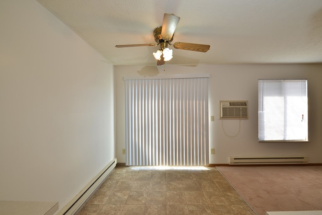 A room with a ceiling fan and a window with blinds.