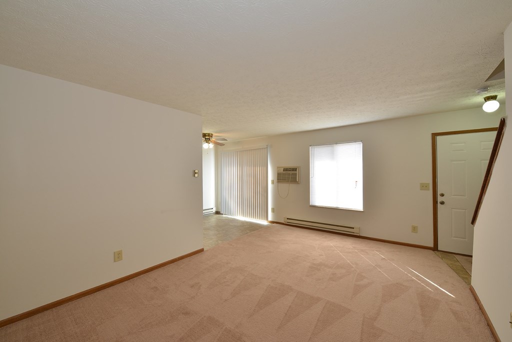 A large empty room with a carpeted floor and white walls.