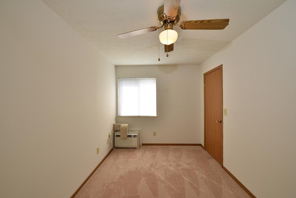 A room with a ceiling fan and a window.