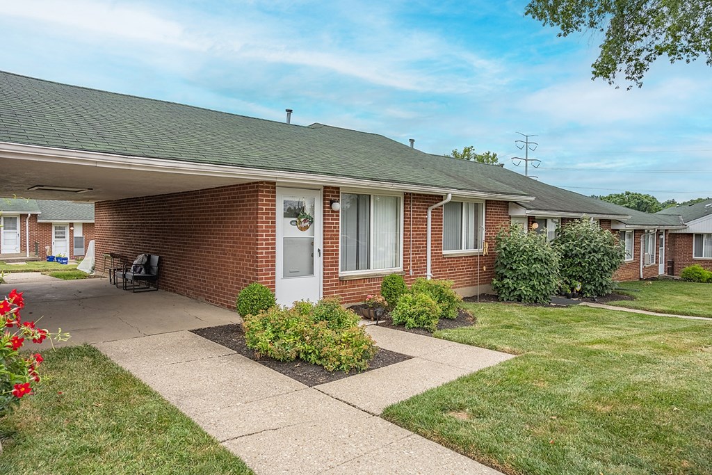 A brick house with a white door and a small garden in front.