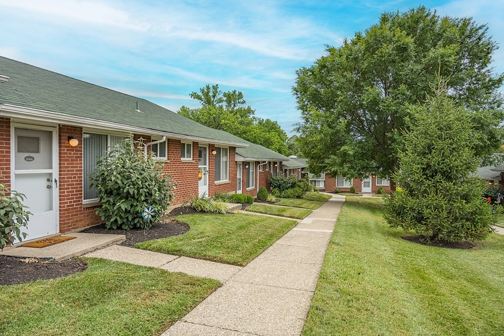 A row of houses with a sidewalk in front.