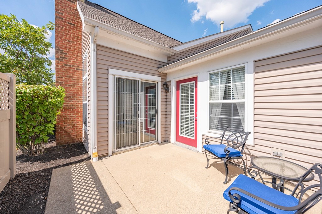 A house with a red door and a blue chair on the porch.